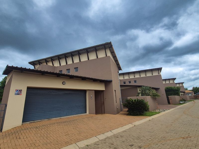 Front elevation of a modern residential property featuring a paved driveway, integrated garage, and contemporary architectural design.