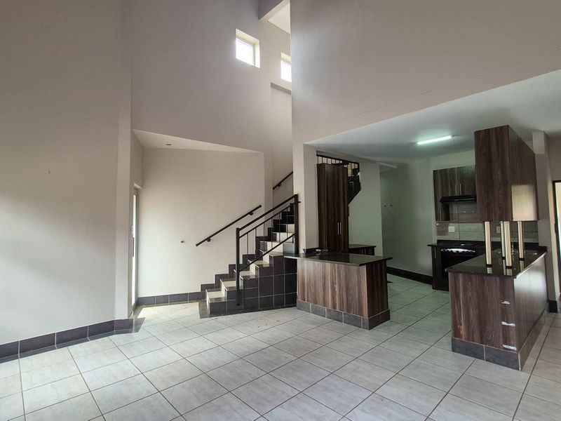 Spacious open-plan living area featuring a modern kitchen with granite countertops, built-in appliances, and a staircase leading to the upper level.