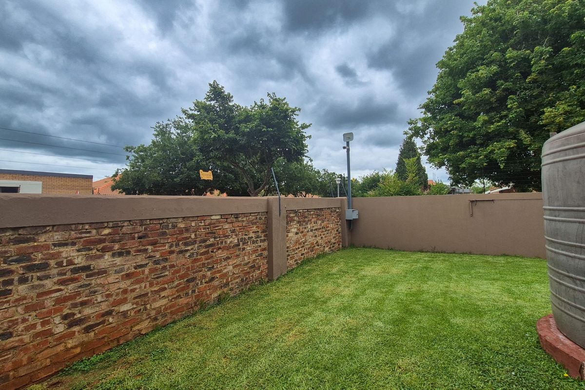 A private rear garden area featuring a brick boundary wall, a water storage tank, and a well-maintained lawn.