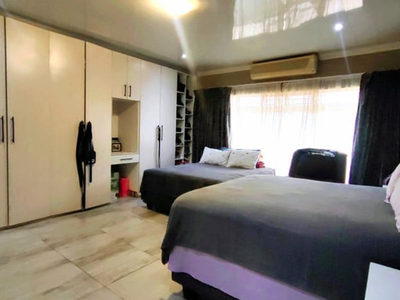 Spacious bedroom featuring extensive built-in cabinetry, tiled flooring, and an integrated air conditioning unit.