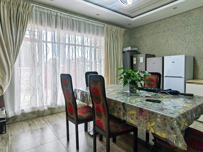 A dining area featuring tiled flooring and a large window with curtains, providing natural light to the space.