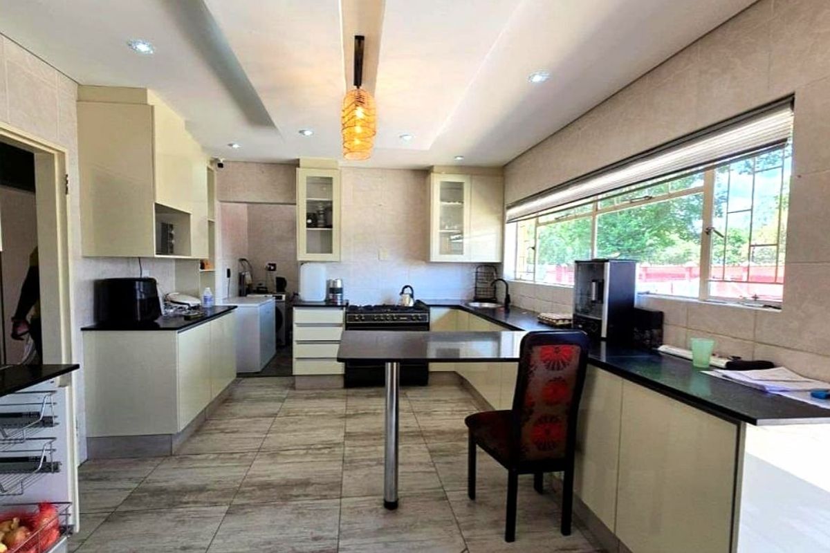 A functional kitchen featuring ample built-in cabinetry, stone countertops, a gas stove, and tiled flooring with a breakfast bar area.