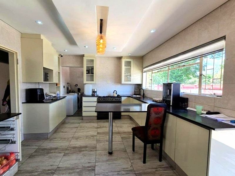A functional kitchen featuring ample built-in cabinetry, stone countertops, a gas stove, and tiled flooring with a breakfast bar area.