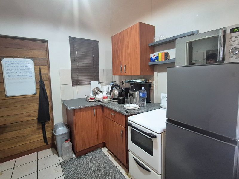 Compact kitchen featuring laminate cabinetry, tiled backsplash, and built-in oven, providing a functional workspace with tiled flooring and a window with venetian blinds.