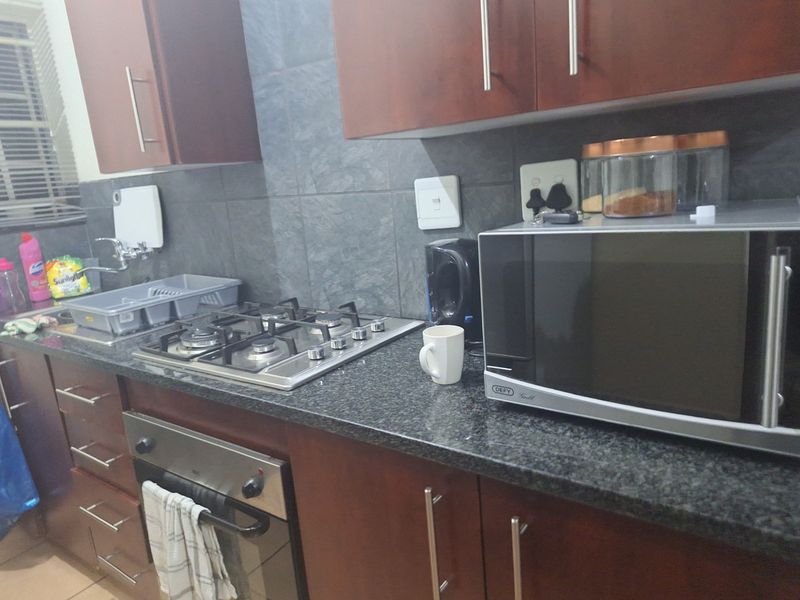 A functional kitchen featuring dark wood cabinetry, granite countertops, a gas hob, and a built-in oven with a tiled backsplash.