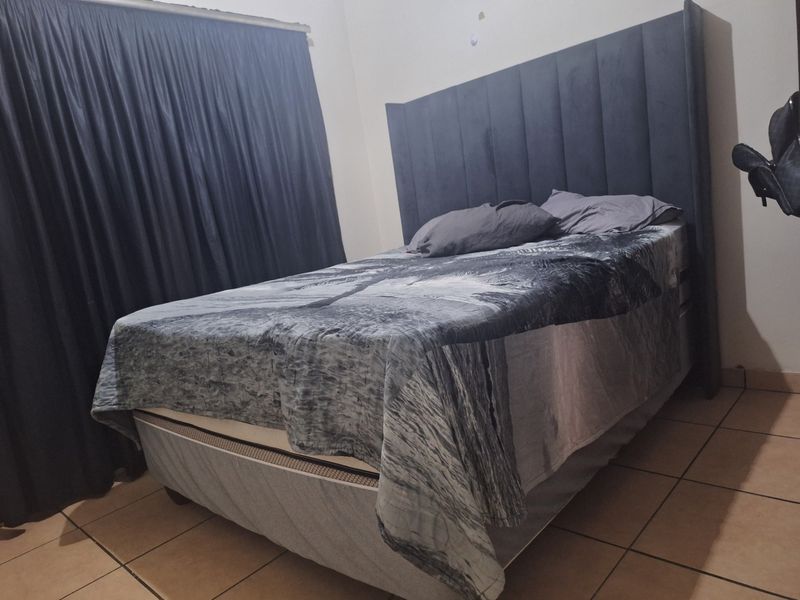 A bedroom featuring tiled flooring and dark curtains, providing a functional sleeping space.