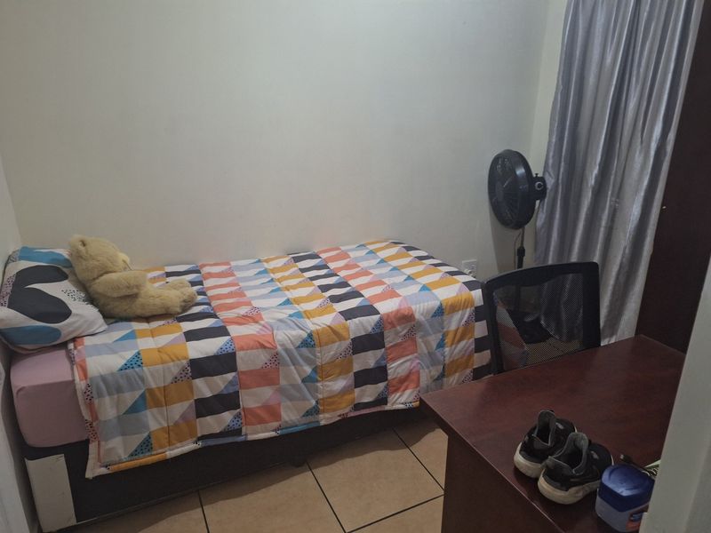 A compact bedroom featuring tiled flooring and neutral wall finishes, suitable for a single bed and study area.