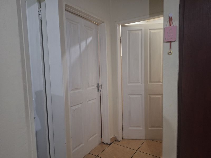 A functional hallway featuring tiled flooring and multiple panelled interior doors providing access to adjacent rooms.