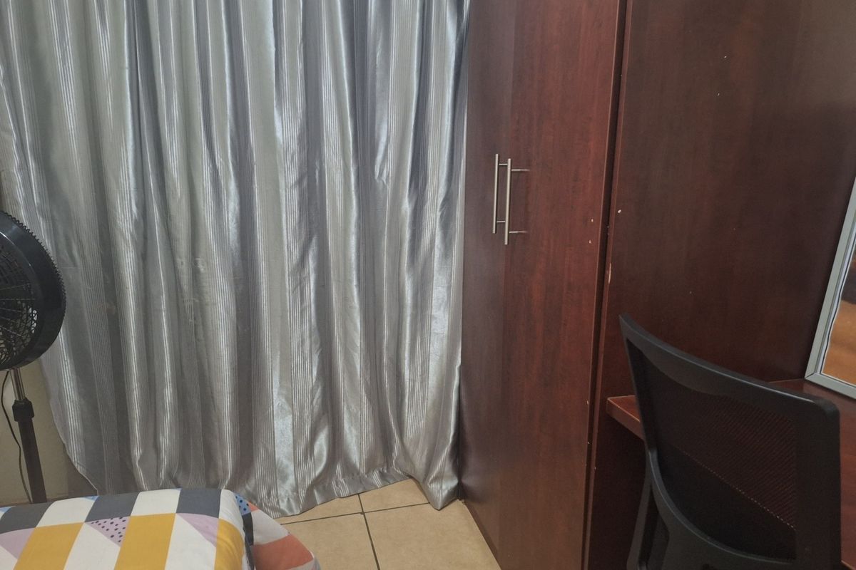 A bedroom featuring tiled flooring and a built-in wooden wardrobe.