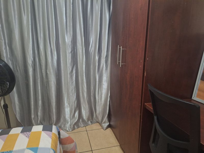 A bedroom featuring tiled flooring and a built-in wooden wardrobe.