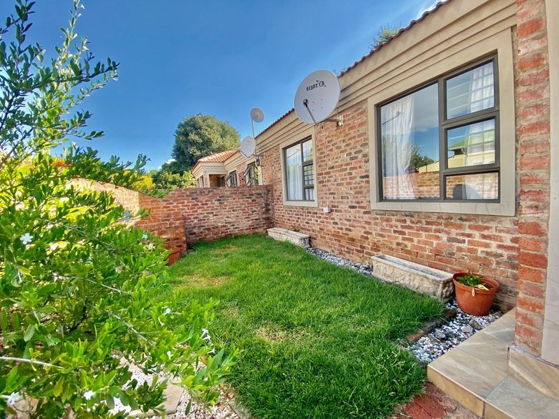 A private rear garden featuring a well-maintained lawn, face brick exterior walls, and paved patio area, providing a low-maintenance outdoor space.