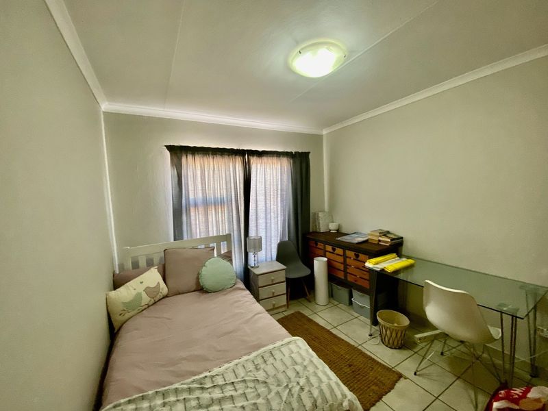 A functional bedroom featuring tiled flooring and a central ceiling light fixture, providing a neutral space ready for personalization.