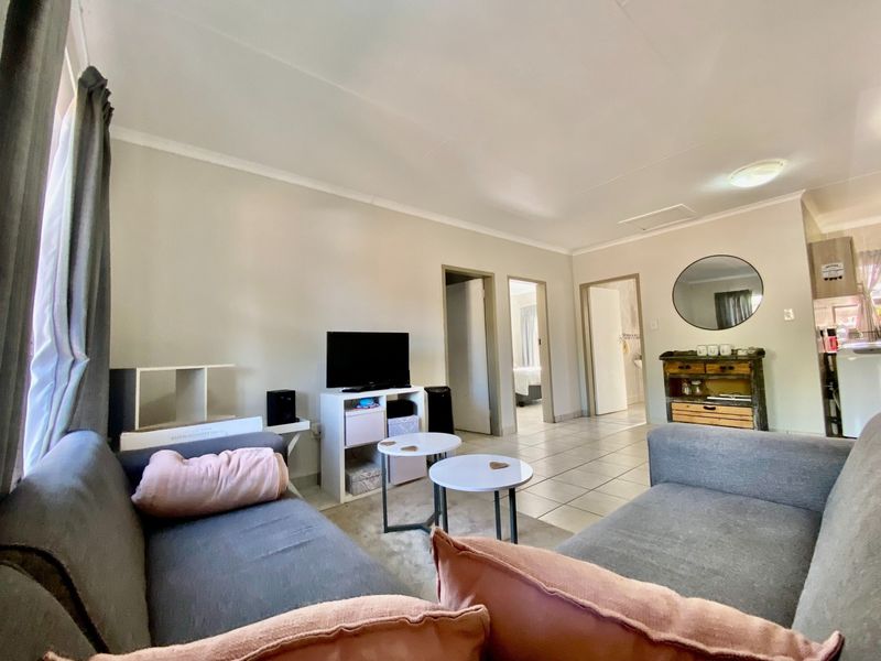 A functional living room area featuring tiled flooring and neutral wall finishes, providing access to adjacent rooms within the townhouse.