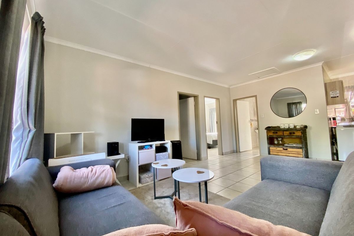 A functional living room area featuring tiled flooring and neutral wall finishes, providing access to adjacent rooms within the townhouse.