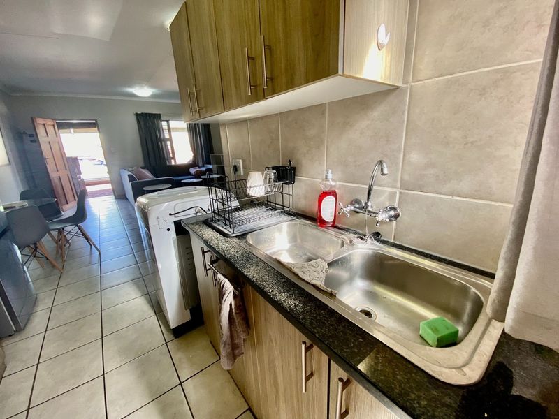 Open plan kitchen area featuring laminate cabinetry, granite countertops, and a double bowl stainless steel sink, flowing into the adjacent living space.