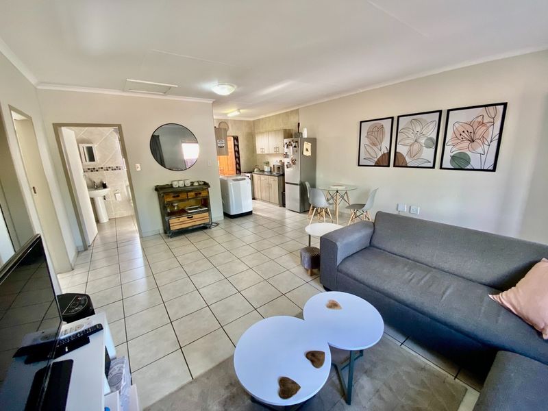Open-plan living area featuring tiled floors, a functional kitchen with cabinetry, and direct access to an adjacent bathroom.