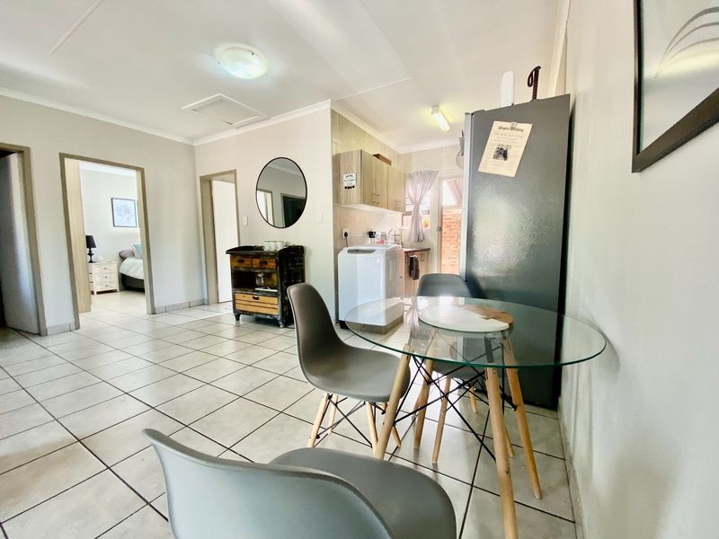 An open-plan living and kitchen area featuring tiled flooring, neutral walls, and direct access to adjacent rooms.