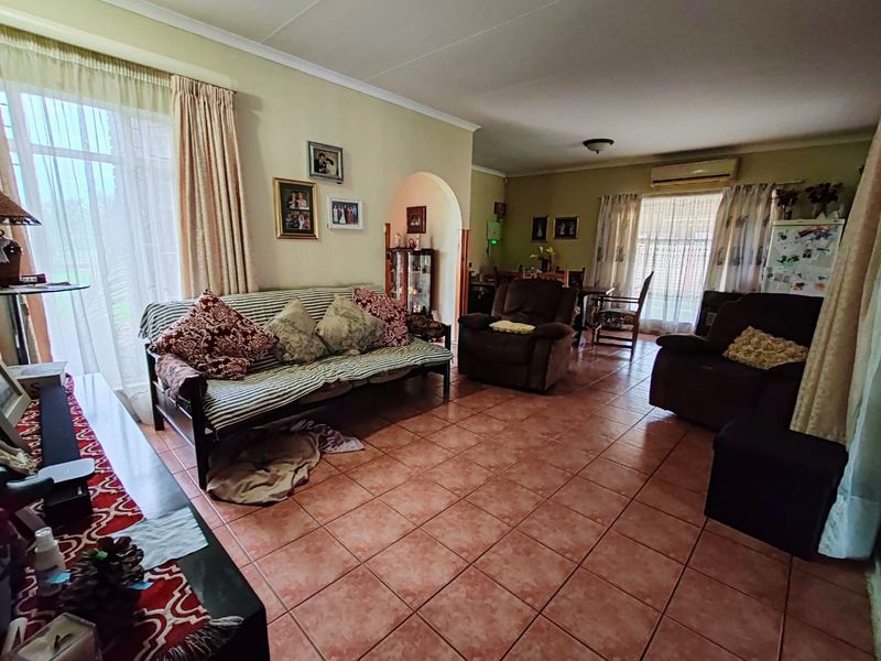 Spacious open-plan living and dining area featuring tiled flooring, an arched transition, and a wall-mounted air conditioning unit.