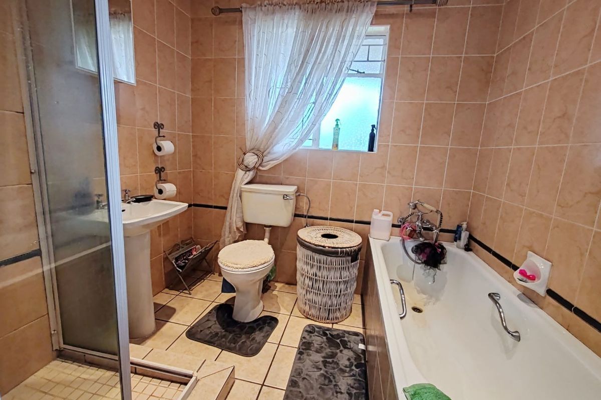 A functional bathroom featuring a pedestal basin, a separate shower enclosure, and a bathtub with tiled wall and floor finishes.