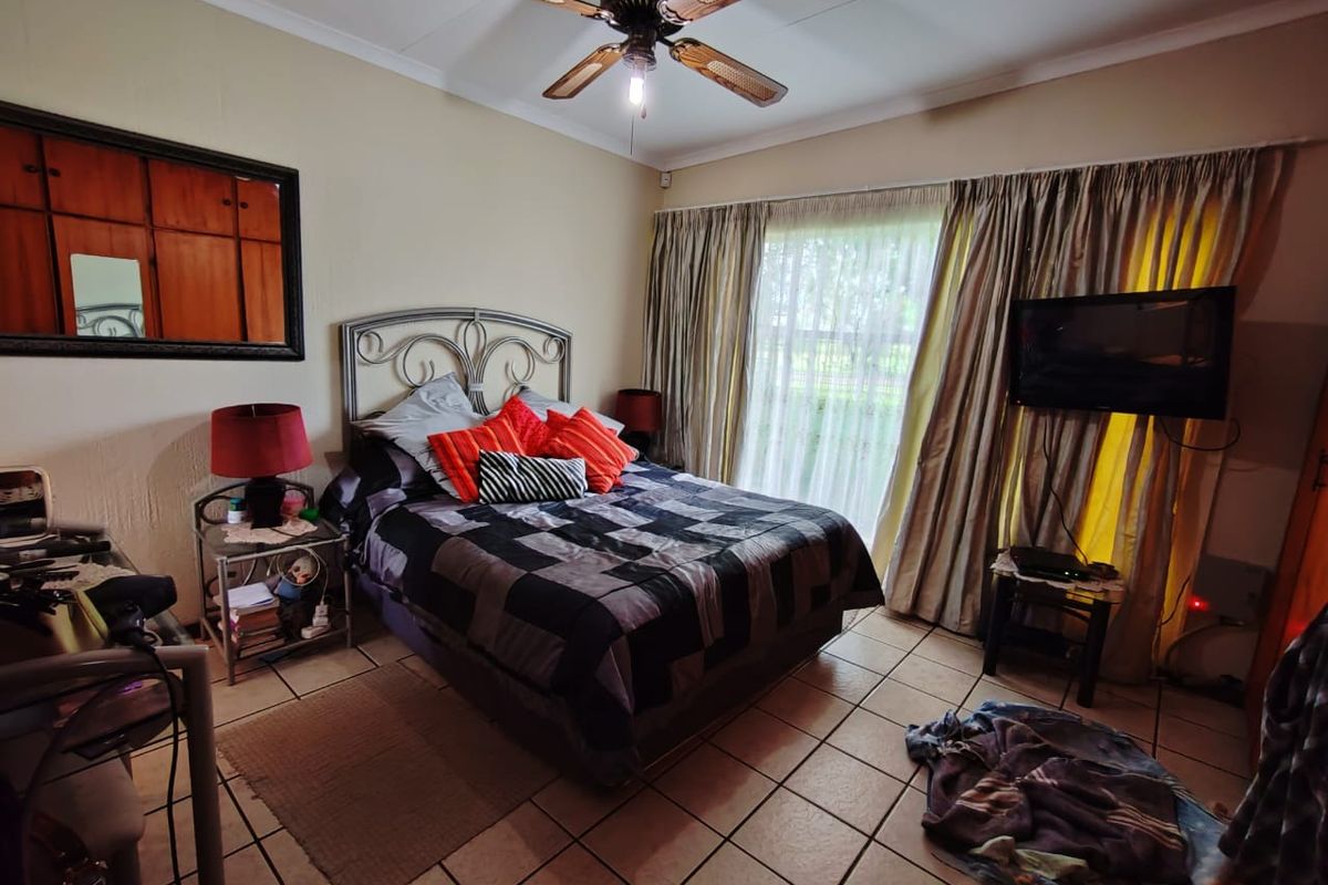 A functional bedroom featuring tiled flooring, a ceiling fan, and built-in cupboards, offering a comfortable and practical living space.