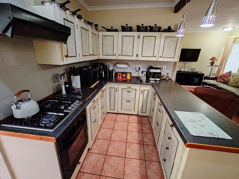 Open-plan kitchen featuring built-in cabinetry, gas hob, oven, and extractor fan, seamlessly flowing into the adjacent living area.