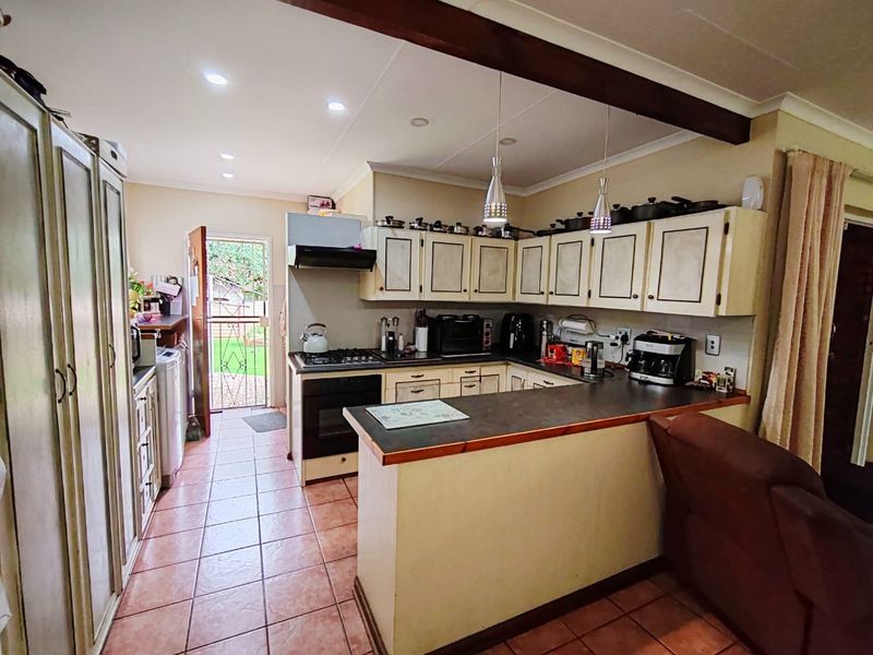 Functional kitchen featuring built-in cabinetry, gas hob, electric oven, and tiled flooring with direct access to the rear garden area.