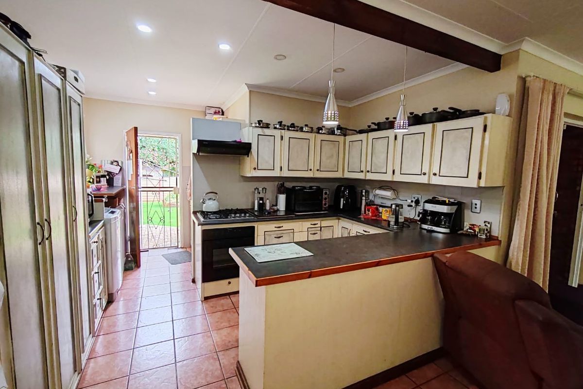Functional kitchen featuring built-in cabinetry, gas hob, electric oven, and tiled flooring with direct access to the rear garden area.