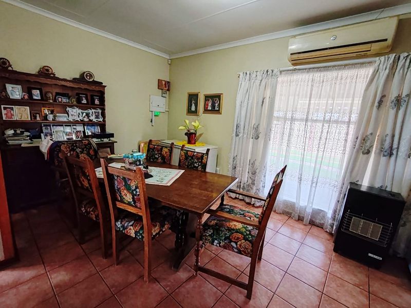 A functional dining room featuring tiled flooring, a wall-mounted air conditioning unit, and a sliding glass door providing access to the exterior.