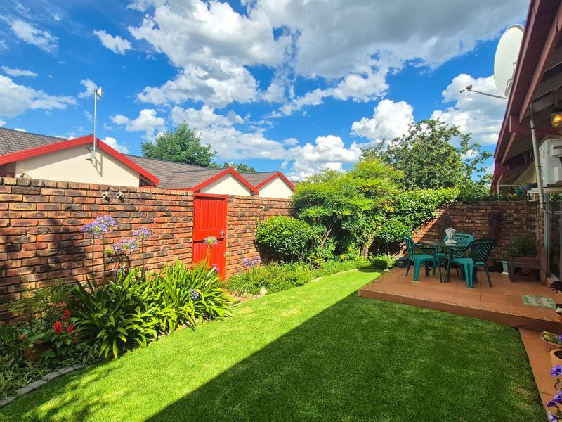 A well-maintained rear garden featuring a brick boundary wall, a paved patio area, and a neat lawn, providing a private outdoor space.
