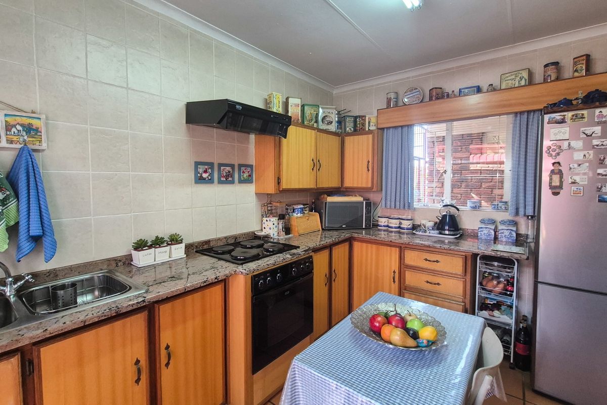 A functional kitchen featuring wooden cabinetry, granite countertops, a built-in oven, hob, extractor fan, and a tiled backsplash.