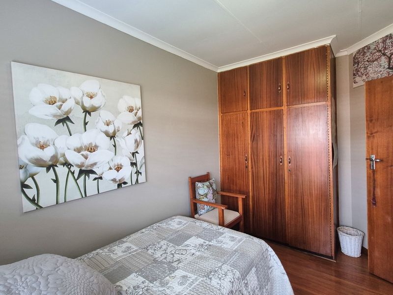 A bedroom featuring built-in wooden wardrobes, laminate flooring, and neutral wall tones, offering a functional and comfortable living space.