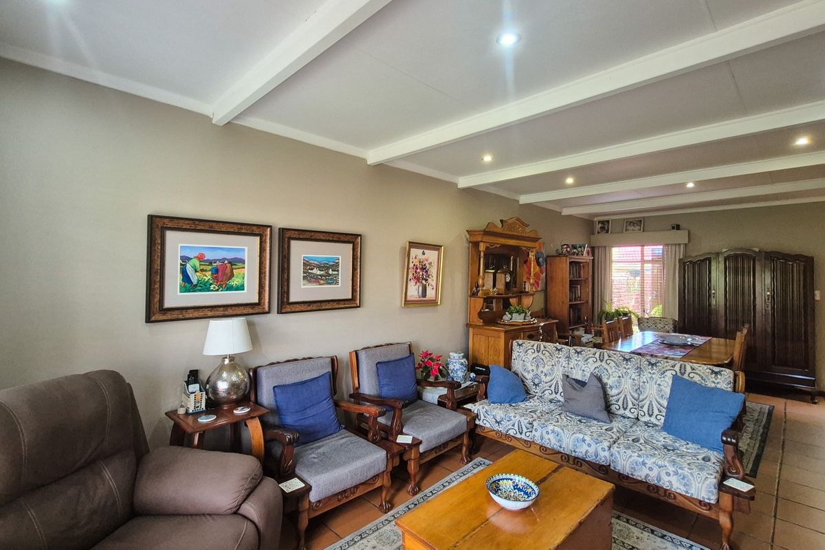 Spacious living area featuring exposed ceiling beams, tiled flooring, and recessed lighting, offering a comfortable and traditional layout.