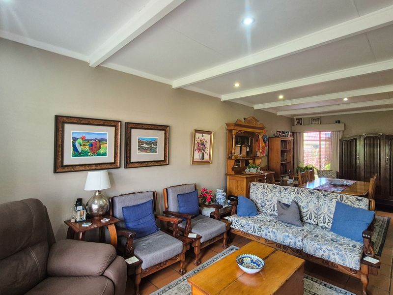 Spacious living area featuring exposed ceiling beams, tiled flooring, and recessed lighting, offering a comfortable and traditional layout.