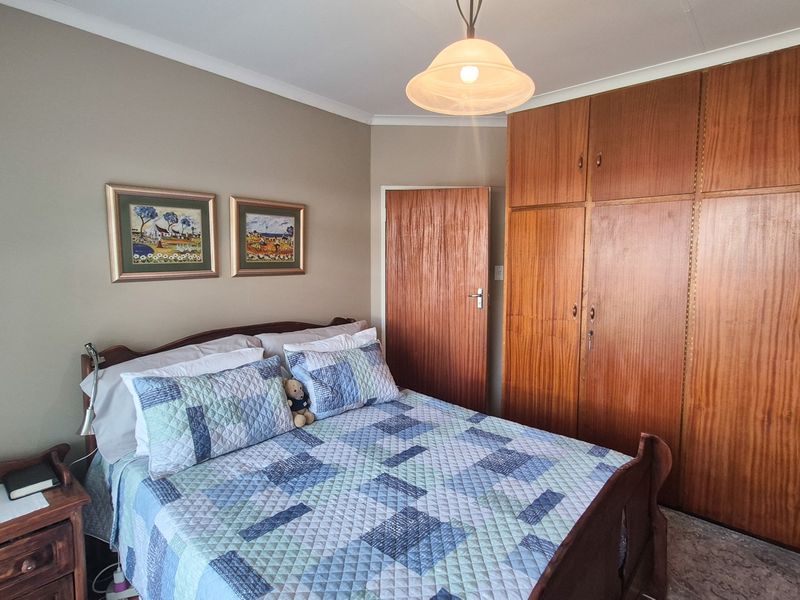 A bedroom featuring extensive built-in wooden cabinetry, neutral wall tones, and classic cove cornicing, offering functional storage space.