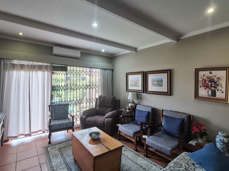 A comfortable living room featuring tiled flooring, recessed ceiling lighting, and a split-system air conditioner, with direct access to the outdoor area via sliding doors.