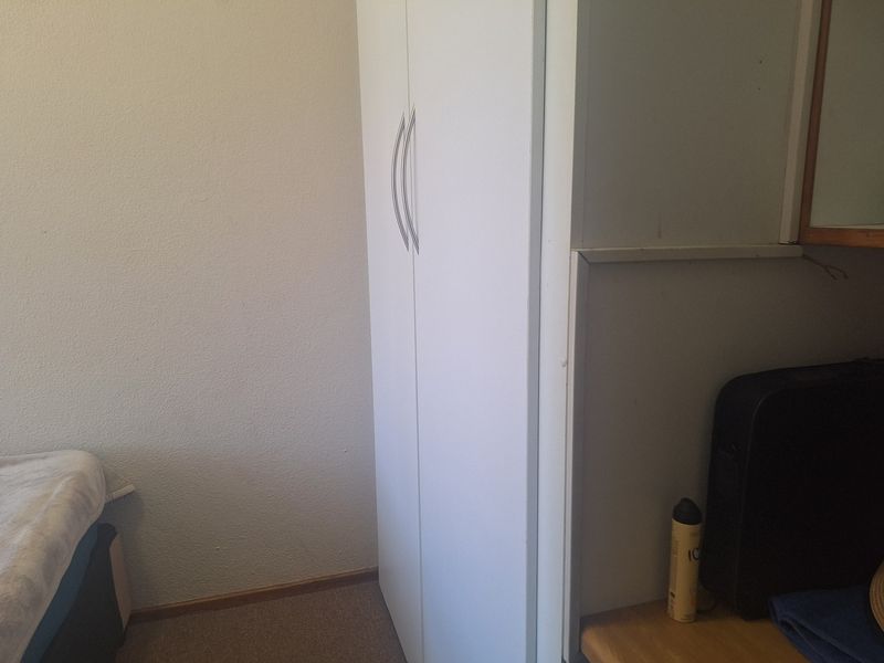 A bedroom interior featuring a white built-in wardrobe with modern handles.