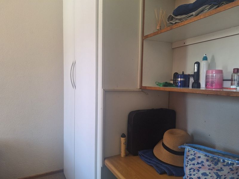 A bedroom corner featuring a white built-in wardrobe and integrated wooden shelving unit for storage.