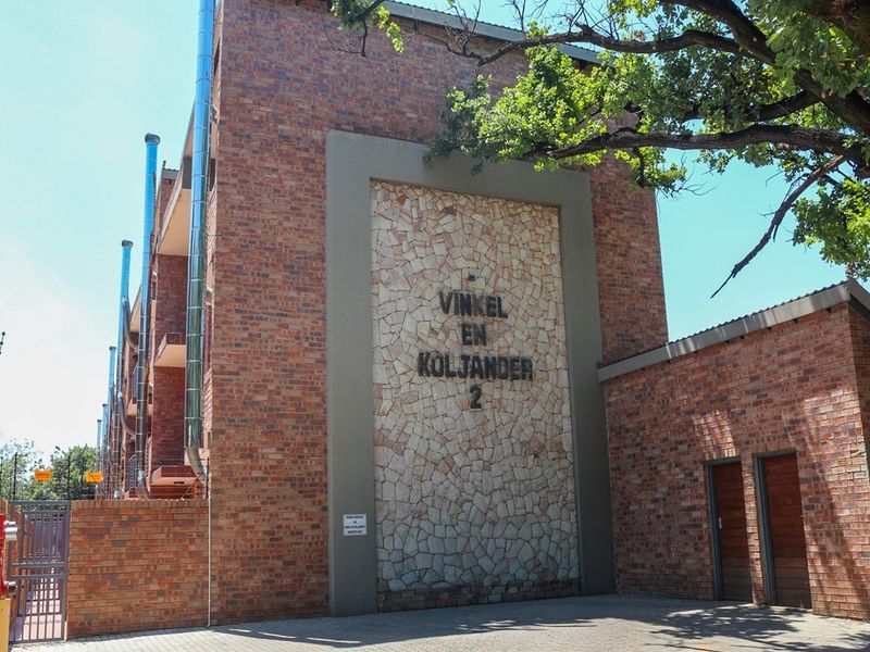 Exterior view of the Vinkel en Koljander 2 apartment complex, featuring a face brick facade, stone cladding detail, and paved entrance area.