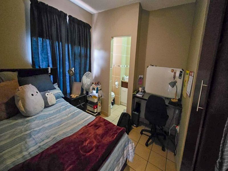 A bedroom featuring a built-in wardrobe and an attached en-suite bathroom with tiled flooring.