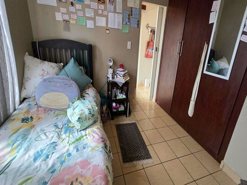 A bedroom featuring tiled flooring and a built-in wooden wardrobe, providing functional storage space within the apartment.