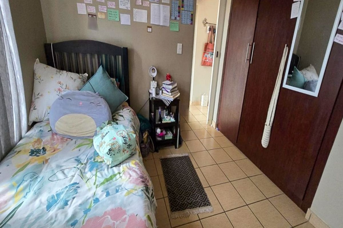 A bedroom featuring tiled flooring and a built-in wooden wardrobe, providing functional storage space within the apartment.