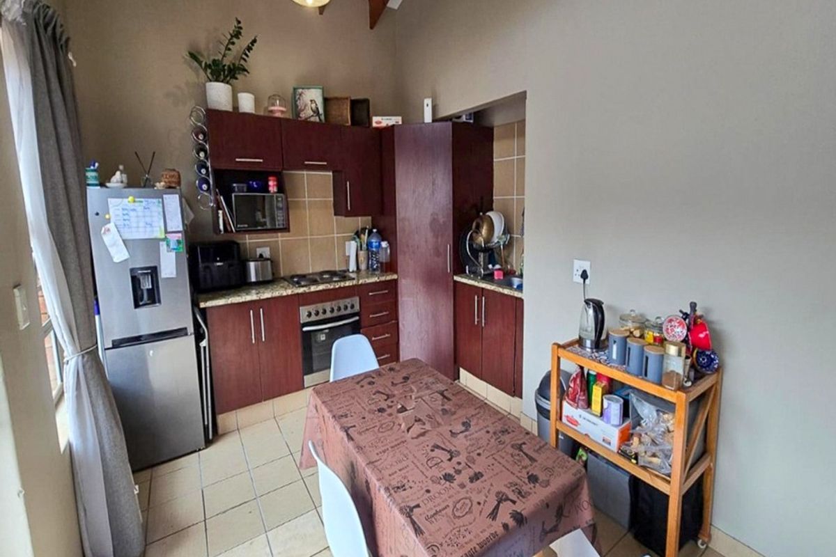 A functional kitchen featuring dark wood cabinetry, granite countertops, tiled backsplash, and exposed timber beams, offering a practical layout for daily cooking and dining.