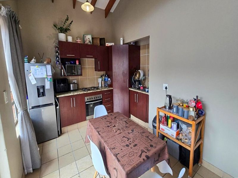 A functional kitchen featuring dark wood cabinetry, granite countertops, tiled backsplash, and exposed timber beams, offering a practical layout for daily cooking and dining.