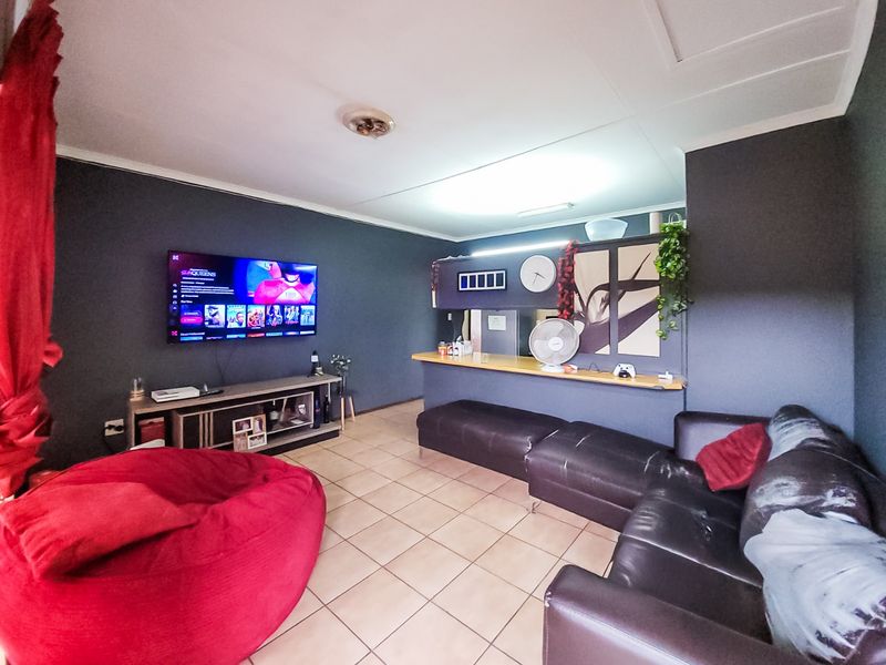 Open-plan living area featuring tiled flooring and a breakfast bar, providing a functional space for relaxation and casual dining.