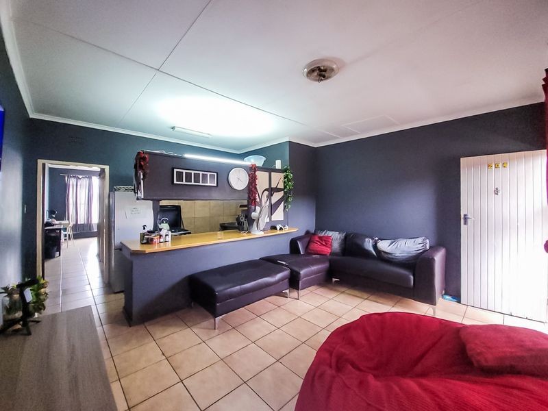 Open-plan living area featuring tiled flooring, a breakfast bar with a pass-through window, and direct access to adjacent rooms.