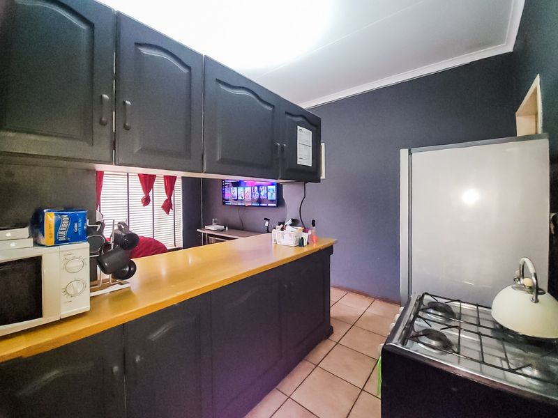 Kitchen featuring dark cabinetry, a breakfast bar, tiled flooring, and a gas stove, offering a functional layout with potential for modern updates.