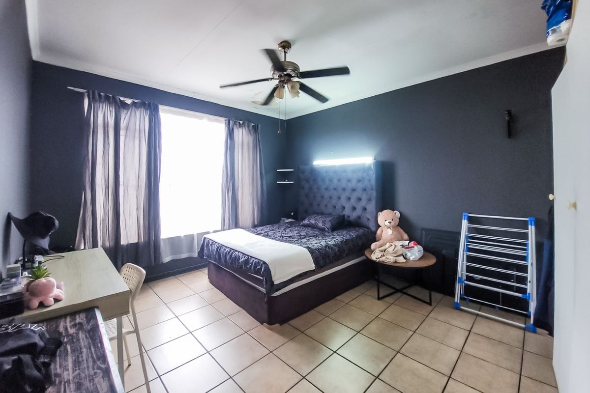 Spacious bedroom featuring tiled flooring, a ceiling fan, and a built-in headboard with integrated lighting.