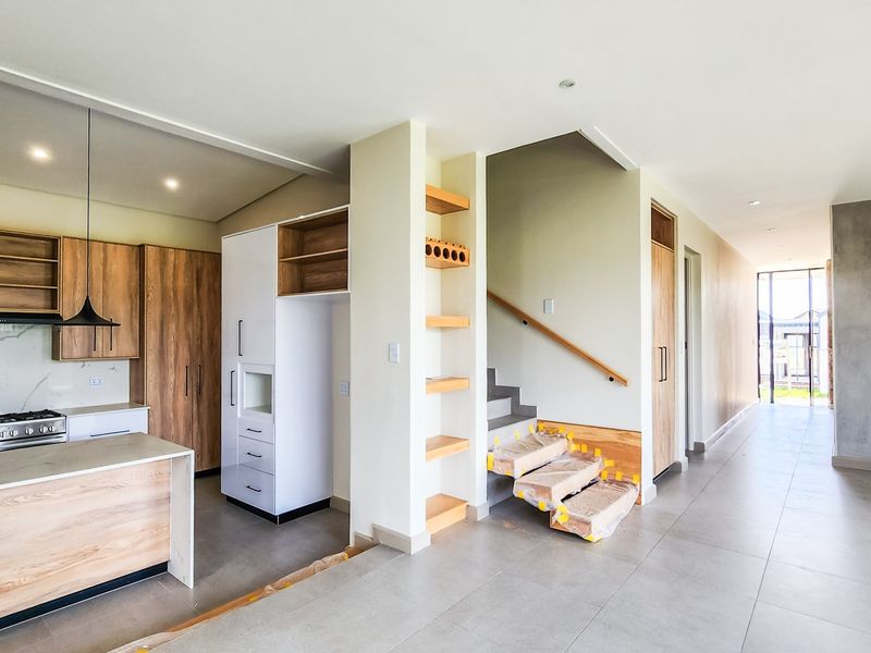 Modern open-plan kitchen and living area featuring contemporary cabinetry, gas cooktop, and staircase, currently in the final stages of completion.