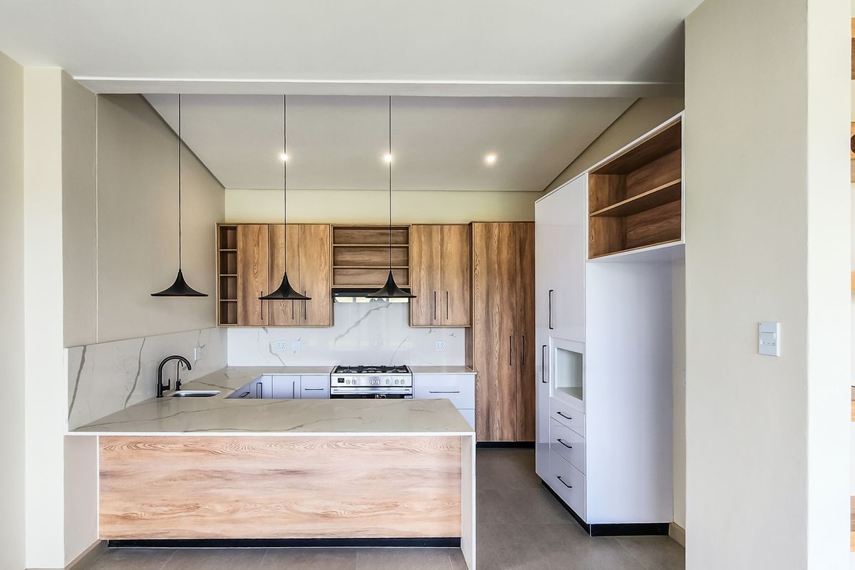Modern kitchen featuring wood-grain cabinetry, stone countertops, integrated gas cooktop, and stylish pendant lighting in a clean, contemporary layout.