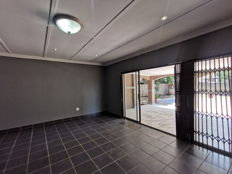 Spacious living area featuring dark tiled flooring, recessed lighting, and large sliding glass doors providing direct access to the outdoor patio area.
